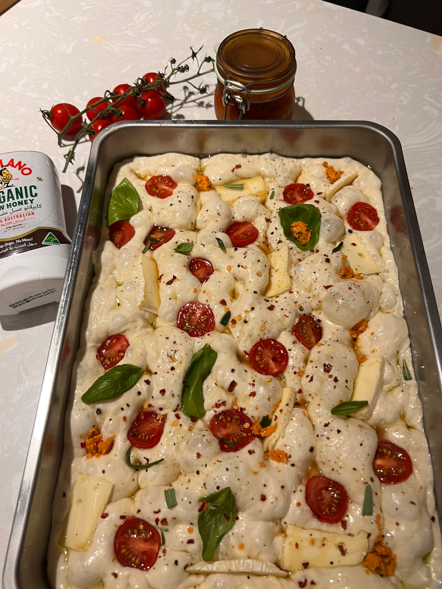 Homemade focaccia with tomatoes, basil and cheese before baking
