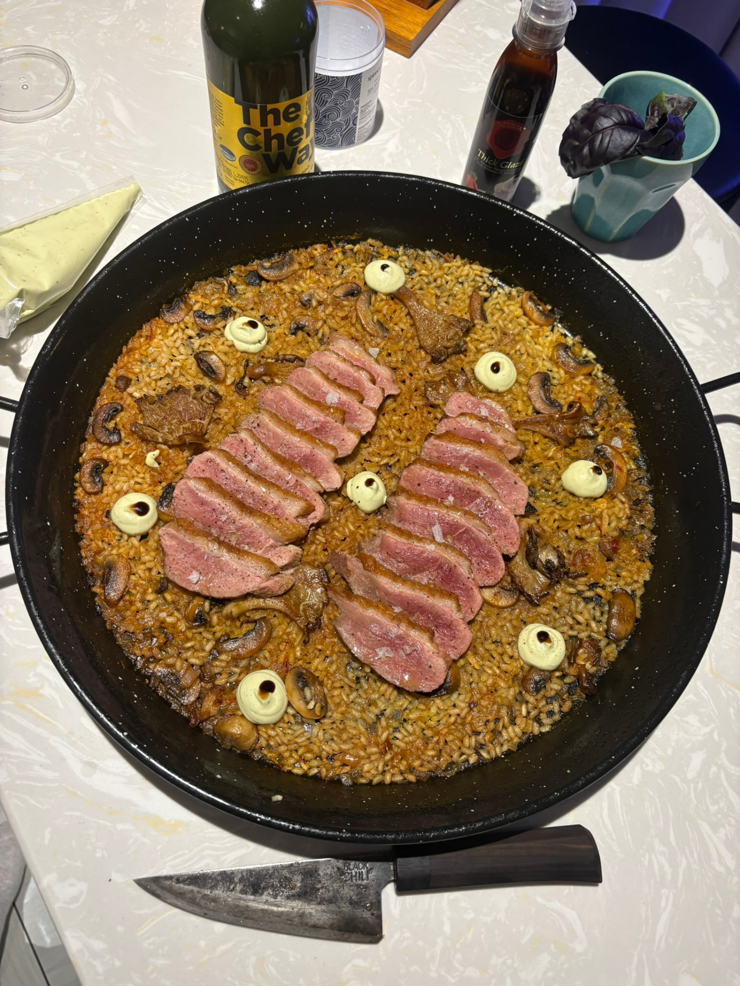 Paella with duck breast and mushrooms in a large pan