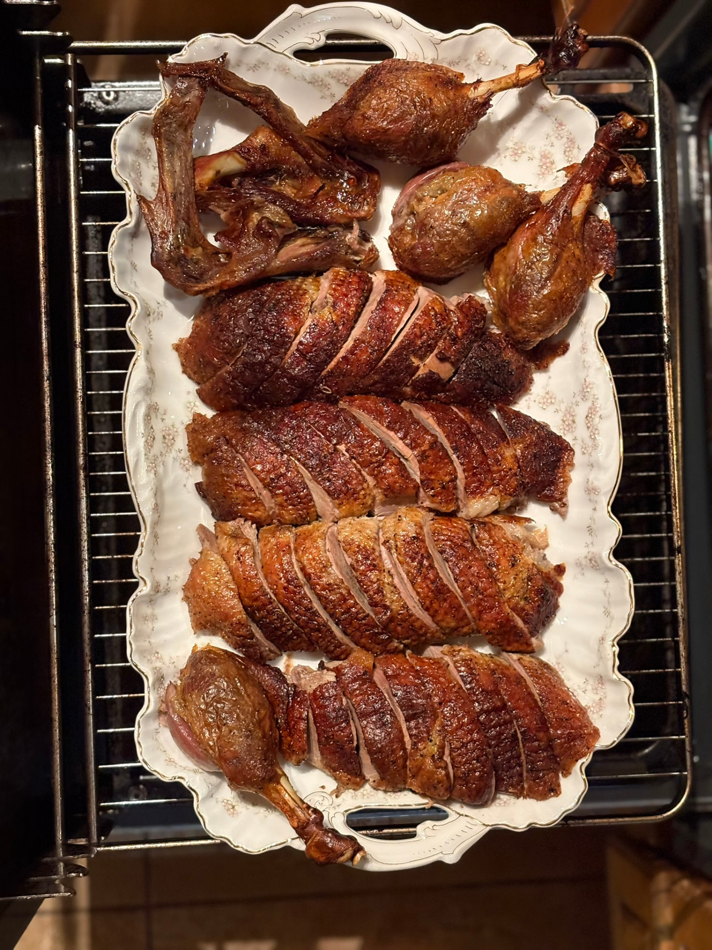 Sliced roast duck breast and legs on a porcelain platter